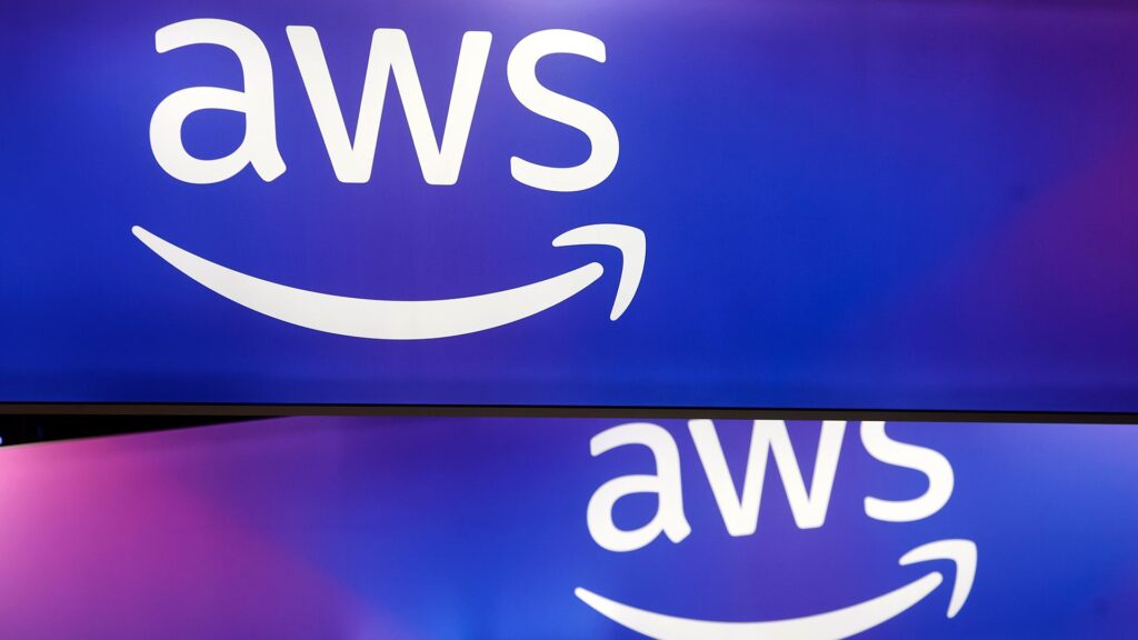 AWS has a chance to show its mettle at re:Invent 2025 A telephoto shot of the AWS logo on two intersecting screens, against a blue and purple gradient background.