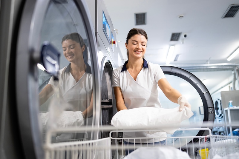 CoreRFID Helps Important Healthcare Obtain Full Lifecycle Traceability: RFID Journal Case Examine Essential Healthcare CoreRFID Dry cleaning service female worker loading industrial washing machine with clothes and linen.