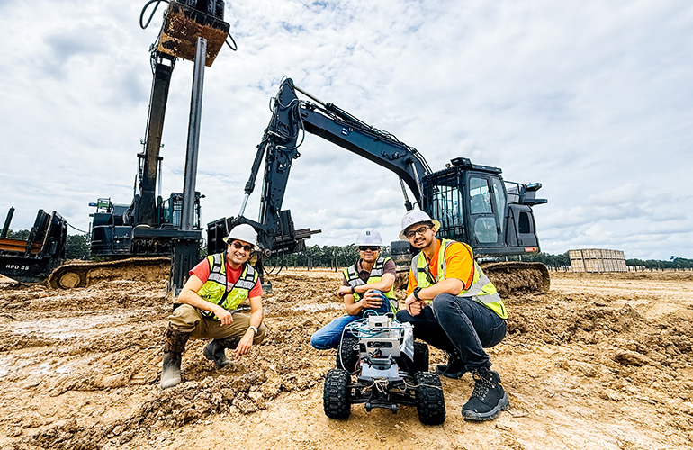 Penn xLAB and Built Robotics Partner to Pioneer Physical AI in Construction two workers stand behind a mobile robot equipped with sensors at a job site.