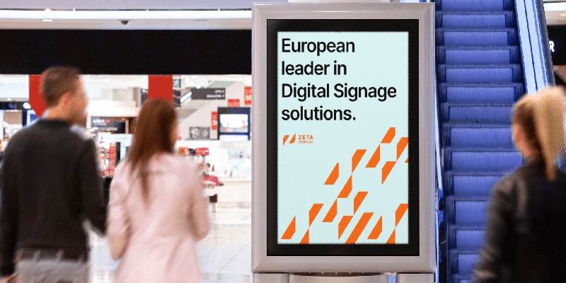 How Com4’s Nordic-Built Connectivity Keeps Europe’s Digital Signage Networks Running ZetaDisplay digital signage screen in a shopping mall reading 'European leader in Digital Signage solutions,' with shoppers passing by near an escalator.