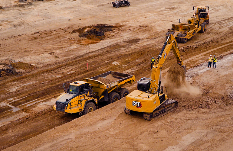 Autonomous Excavation Has Arrived: Bedrock Robotics Debuts Its First Operator-Free Machines on the Job drone image of a bedrock robotics equipped excavator moving dirt.