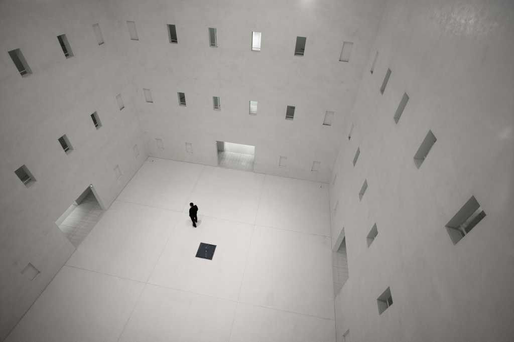 Race Against Time: The Closing Window of Cyber AI Parity Black and white image of a man in a tiled room with many opoen doors and windows