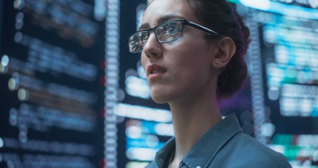 A Silent Threat Hides Within the AI Tool Your Devs Rely On Close Up Portrait of Woman Working on Computer, Lines of Code Language Reflecting on her Glasses from Big Display Screens. Female Programmer Developing New Software, Coding, Managing Cybersecurity